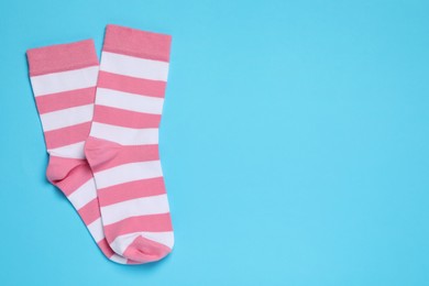 Photo of Pair of new striped sock on light blue background, flat lay. Space for text