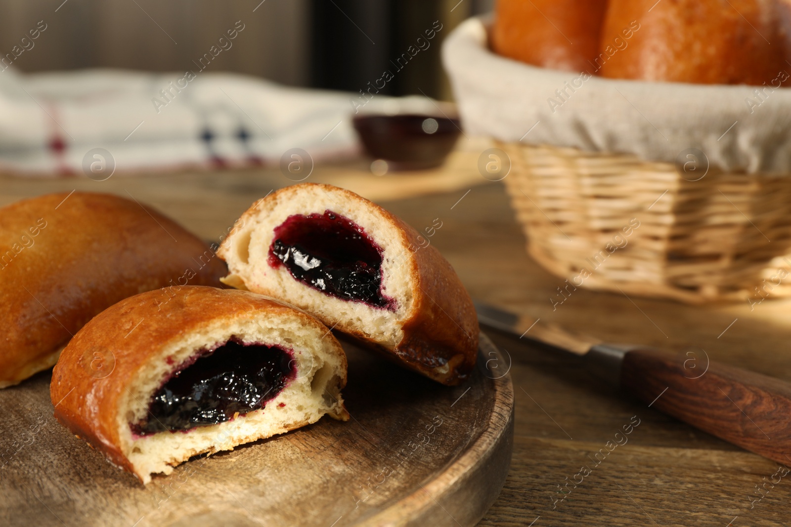 Photo of Delicious baked patties with jam on wooden table, closeup. Space for text