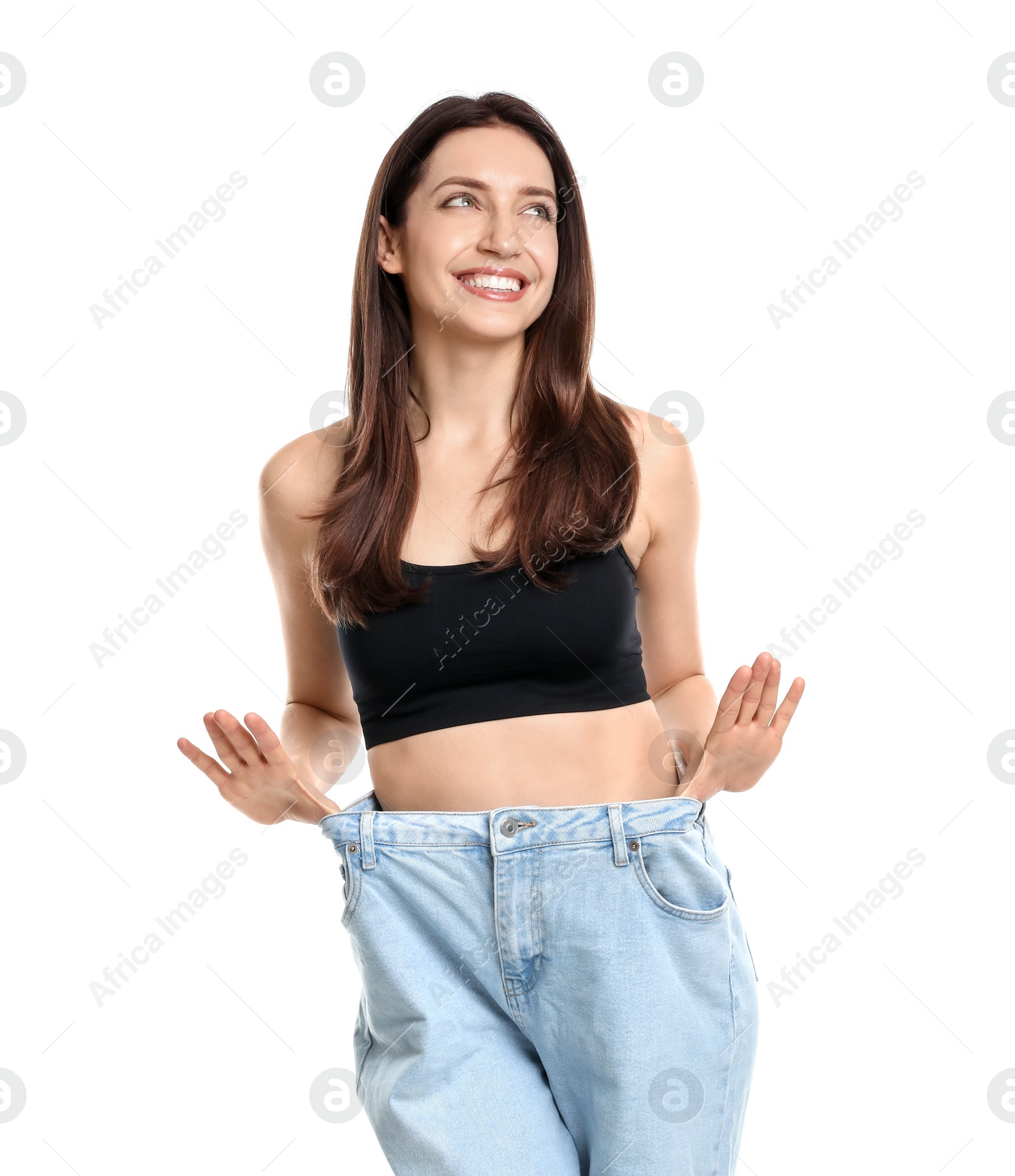 Photo of Happy young woman in big jeans showing her slim body on white background