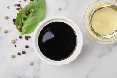 Bowl with balsamic vinegar and ingredients on white marble table, flat lay