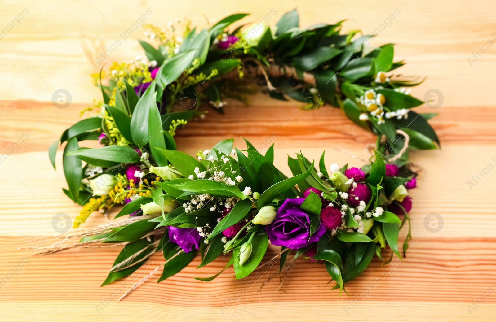 Photo of Beautiful wreath made of flowers and leaves on wooden background