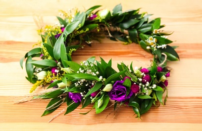 Beautiful wreath made of flowers and leaves on wooden background