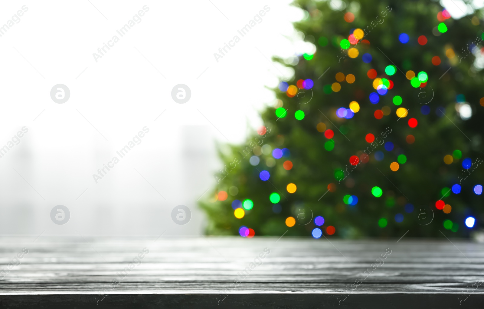 Photo of Empty table and blurred fir tree with colorful Christmas lights on background, bokeh effect. Space for design