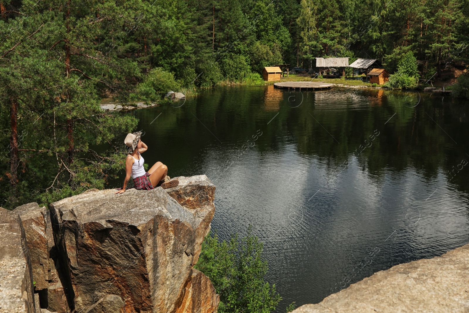 Photo of Young woman on rocky mountain near lake. Camping season