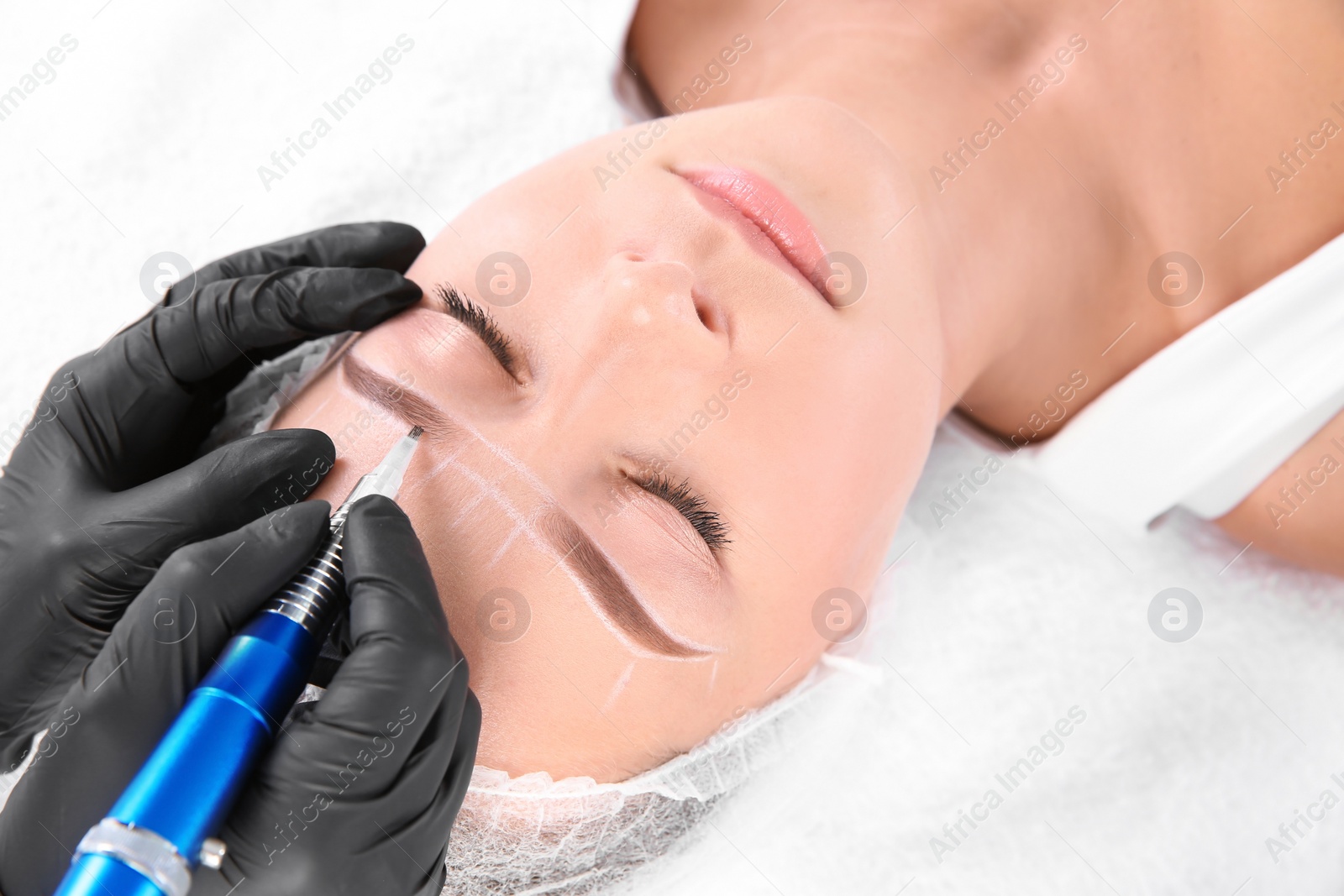 Photo of Young woman undergoing eyebrow correction procedure in salon