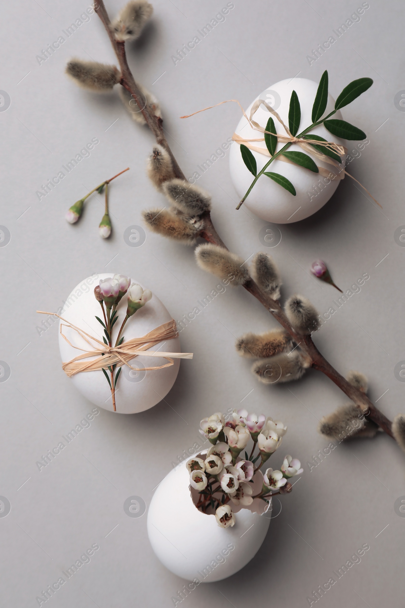 Photo of Flat lay composition with chicken eggs and floral decor on light grey background. Happy Easter