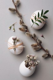 Flat lay composition with chicken eggs and floral decor on light grey background. Happy Easter