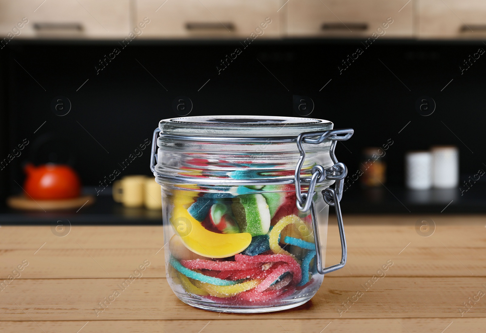 Image of Glass jar with tasty gummy candies on wooden table in kitchen