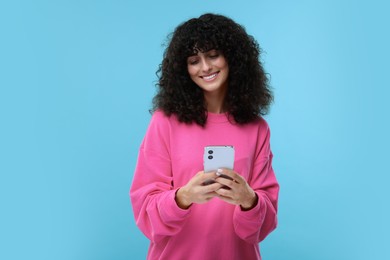 Photo of Woman sending message via smartphone on light blue background, space for text