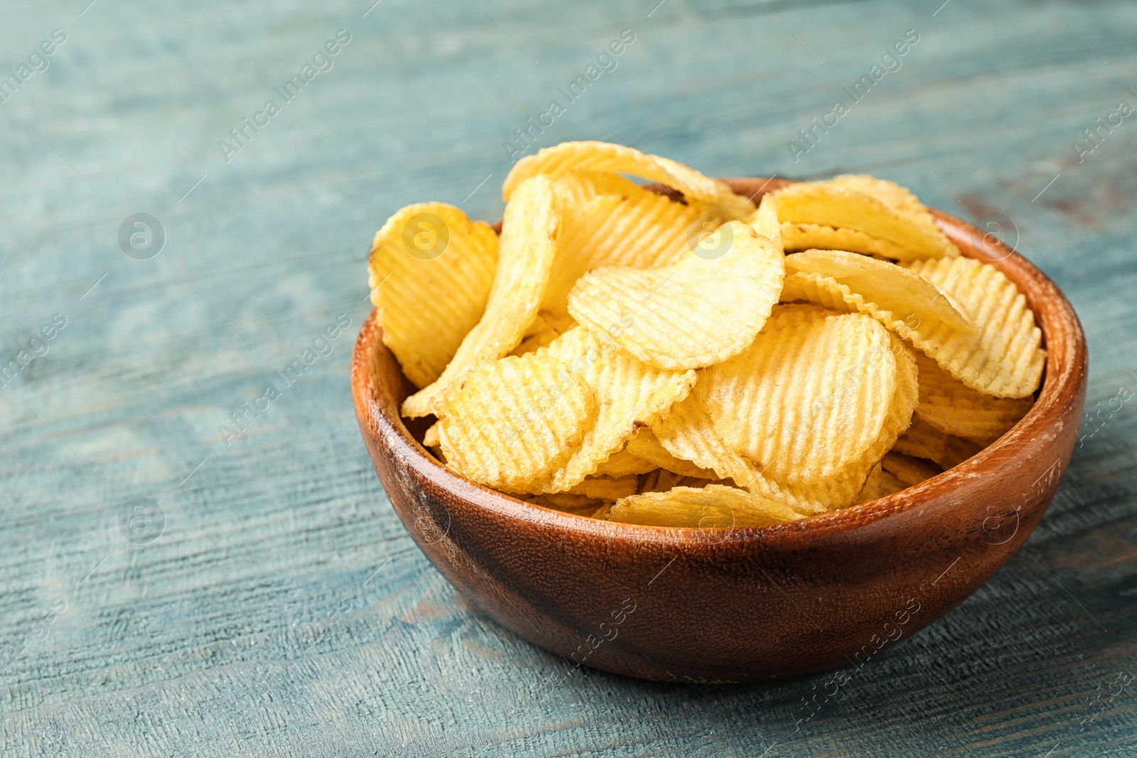 Photo of Delicious crispy potato chips in bowl on table, space for text