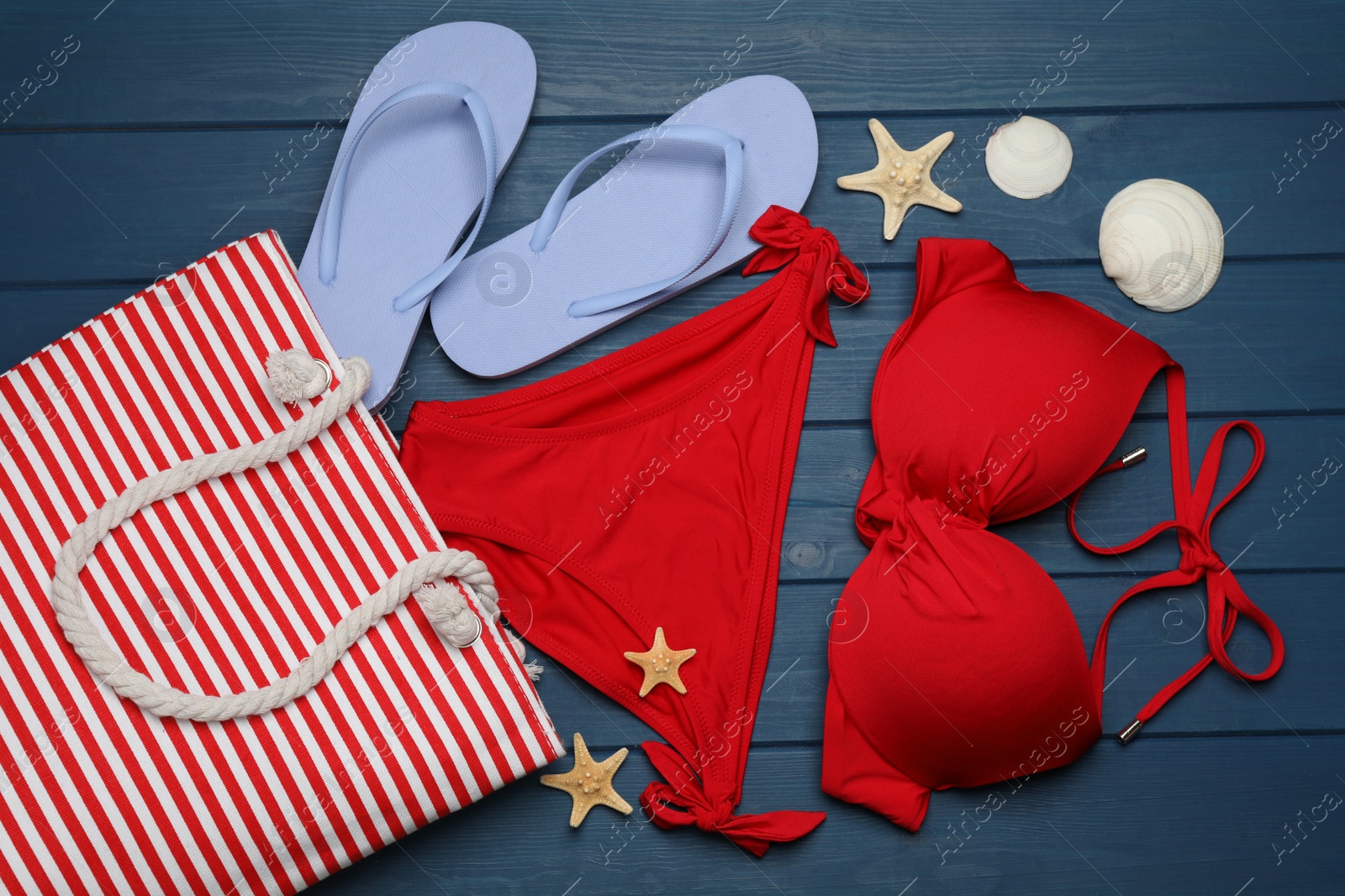 Photo of Stylish bag and beach accessories on blue wooden background, flat lay