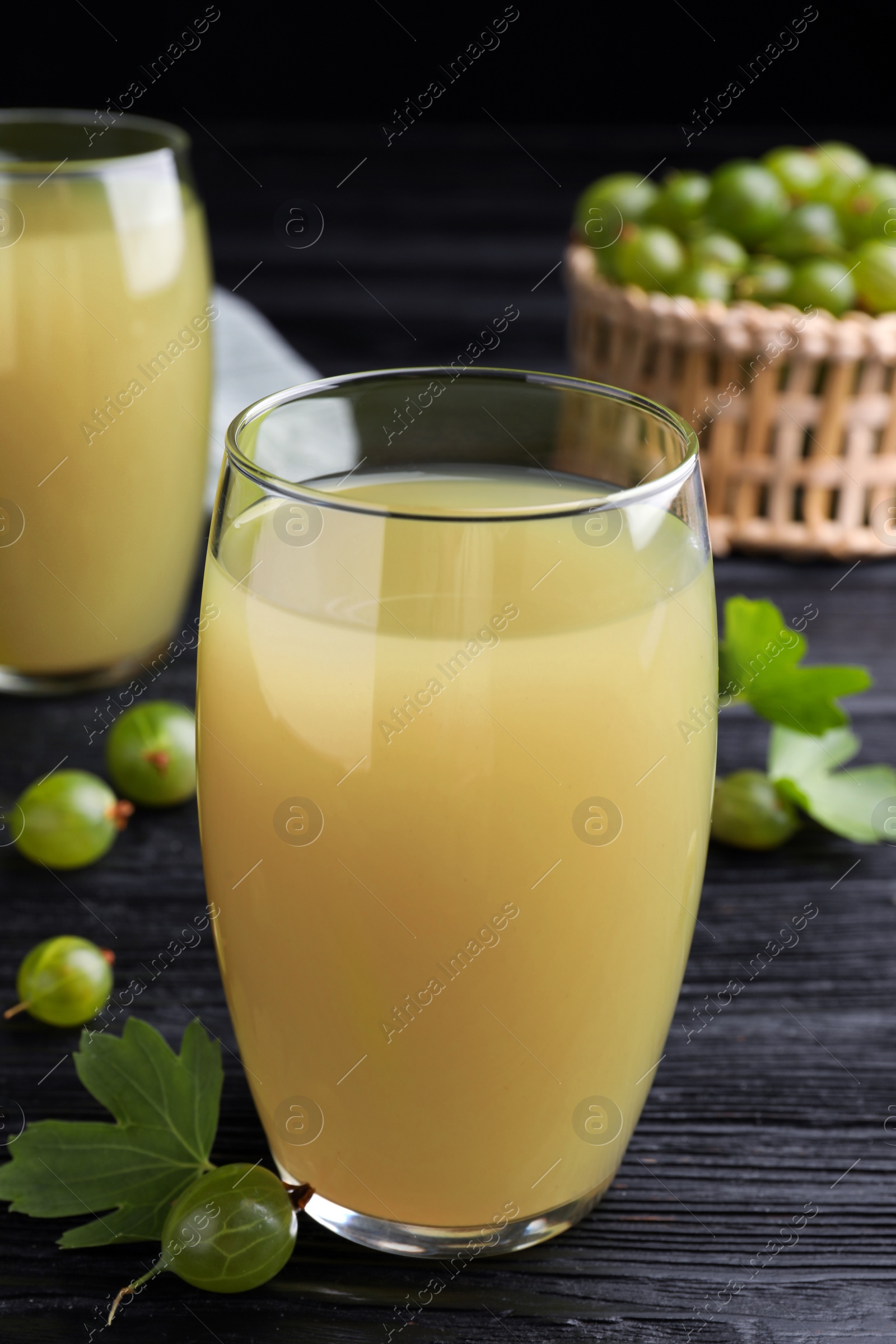 Photo of Tasty gooseberry juice on black wooden table, closeup