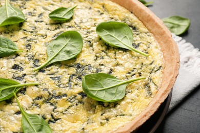 Photo of Delicious homemade spinach pie on black table, closeup