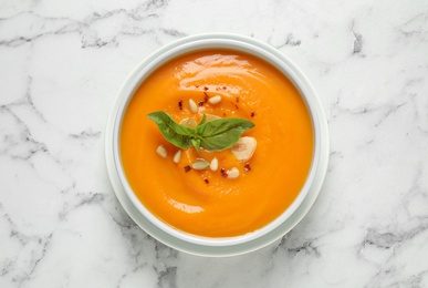 Photo of Delicious pumpkin soup in bowl on marble table, top view