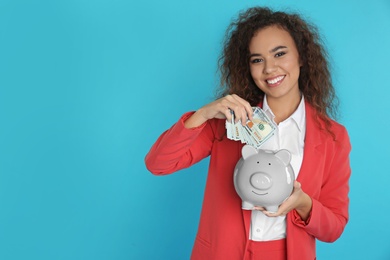 African-American businesswoman with piggy bank and money on color background. Space for text