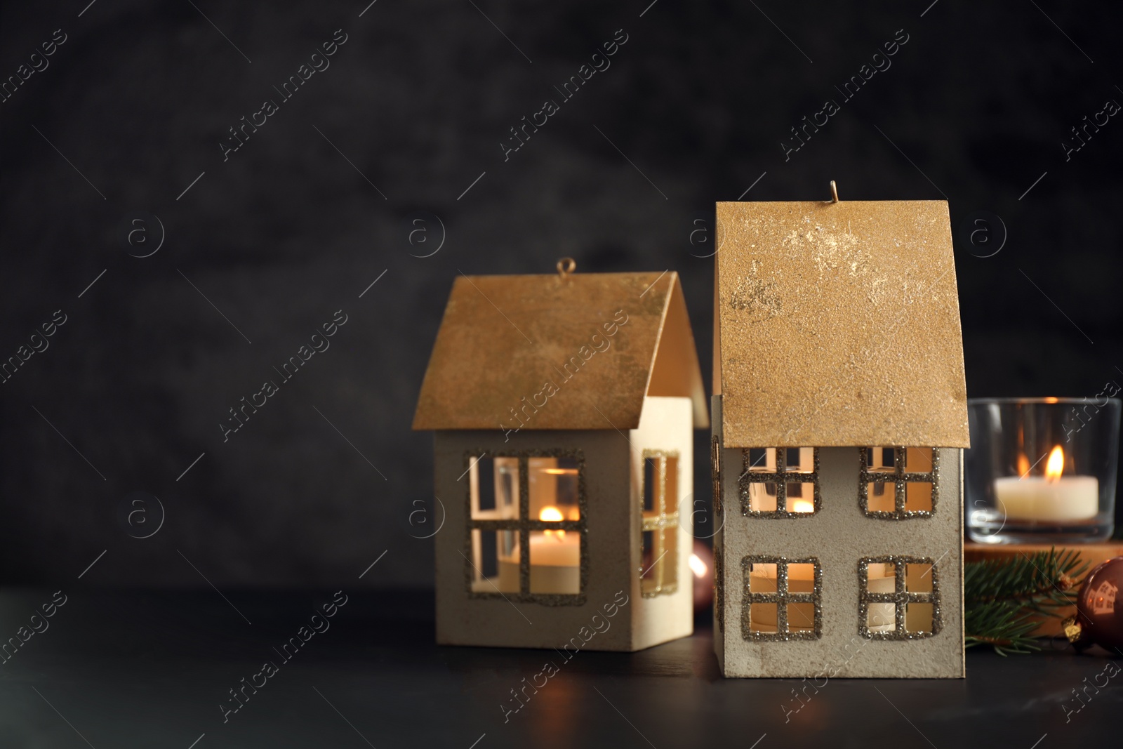 Photo of Composition with house shaped candle holders on dark background, space for text. Christmas decoration