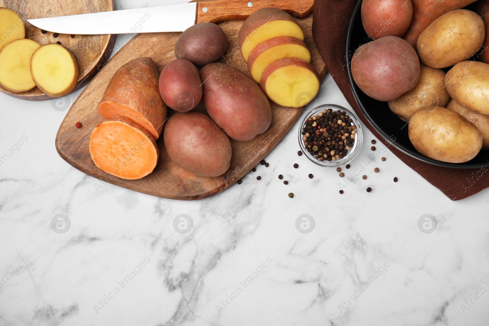 Photo of Different types of fresh potatoes on white marble table, flat lay. Space for text