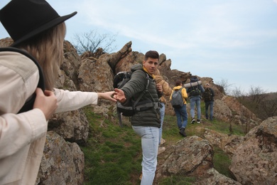 Group of hikers with backpacks climbing up mountains