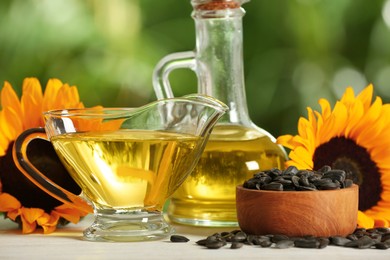 Sunflower cooking oil, seeds and yellow flowers on white wooden table outdoors, closeup