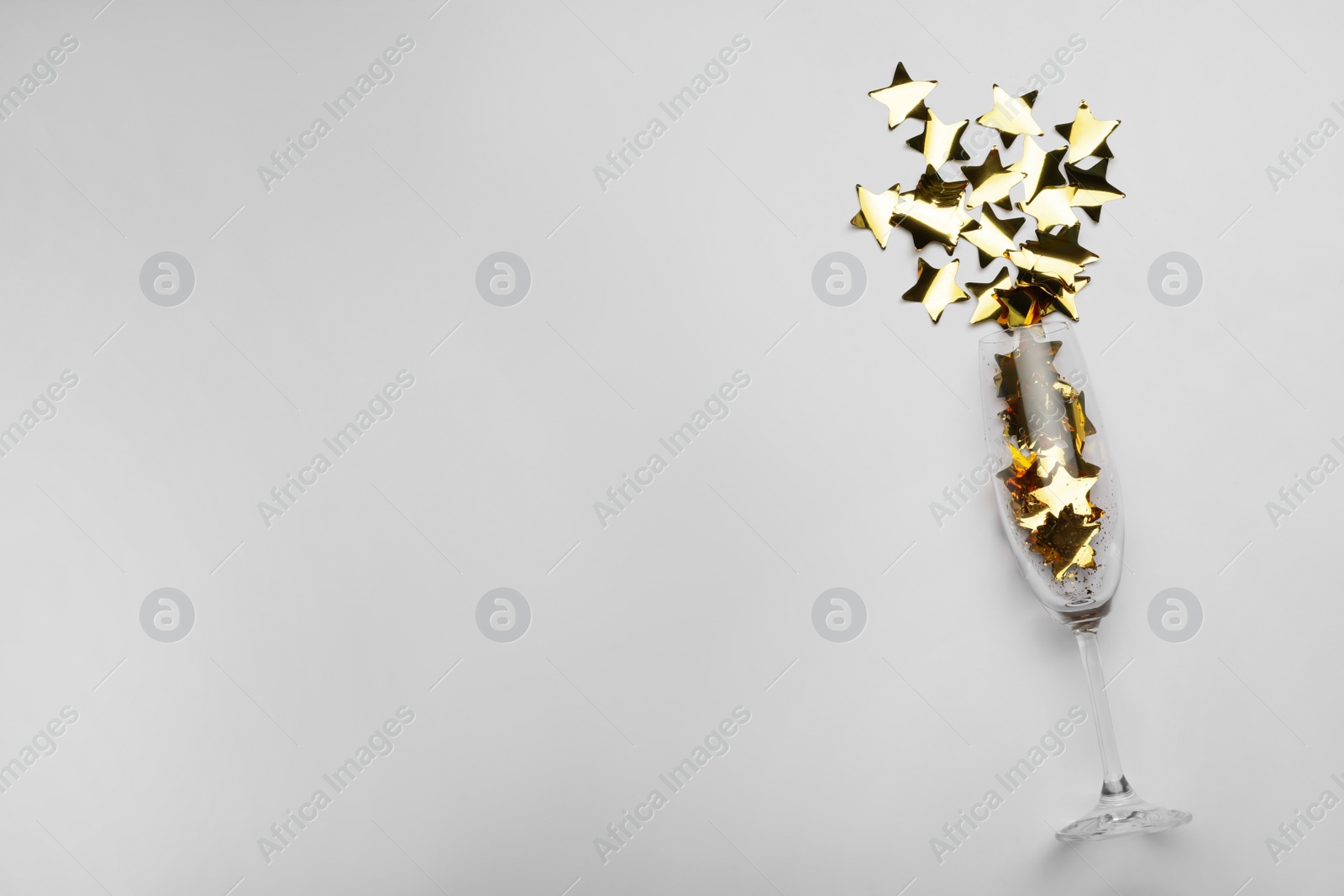 Photo of Flat lay composition with confetti and champagne glass on light background. Space for text