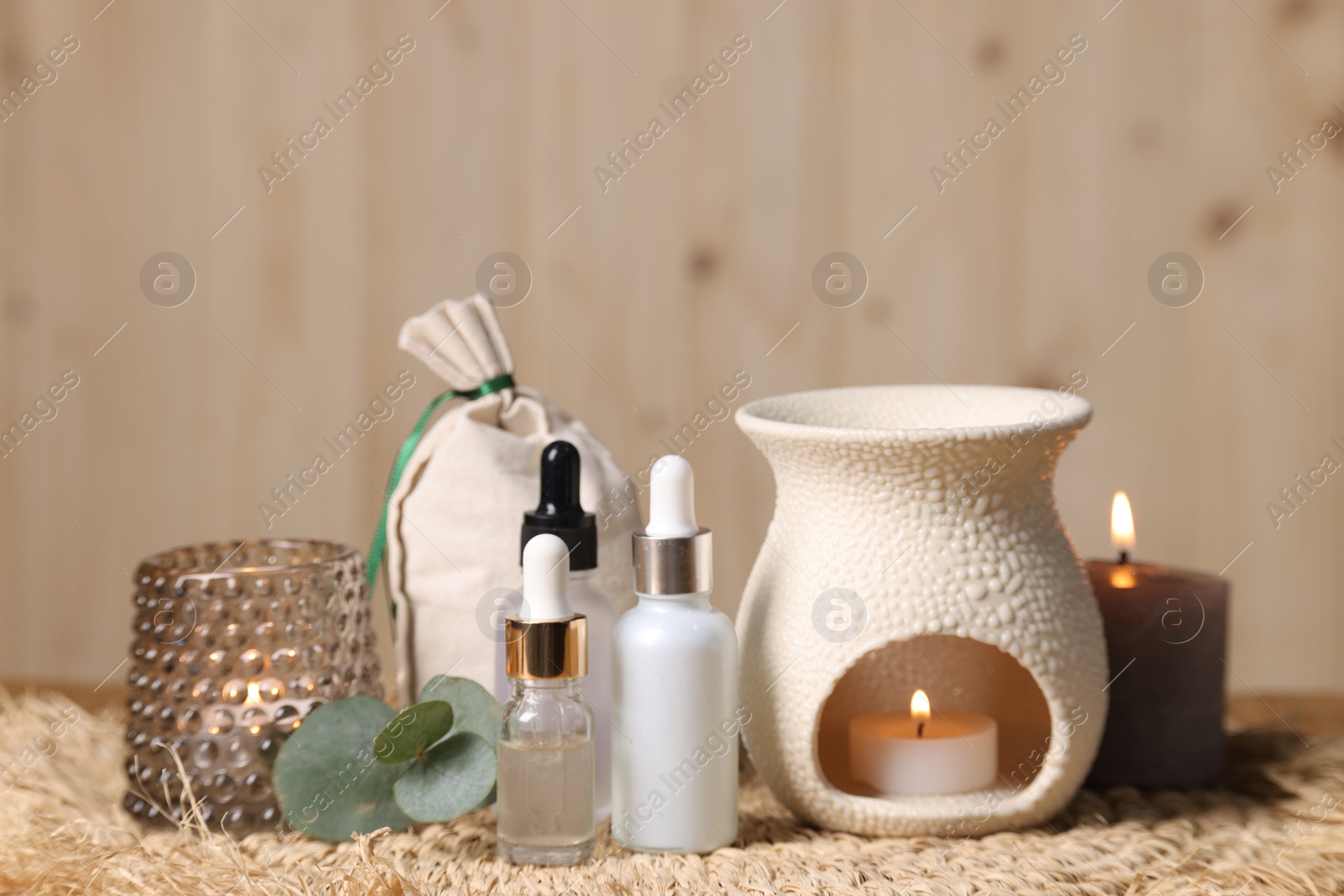 Photo of Different aromatherapy products, burning candles and eucalyptus leaves on table