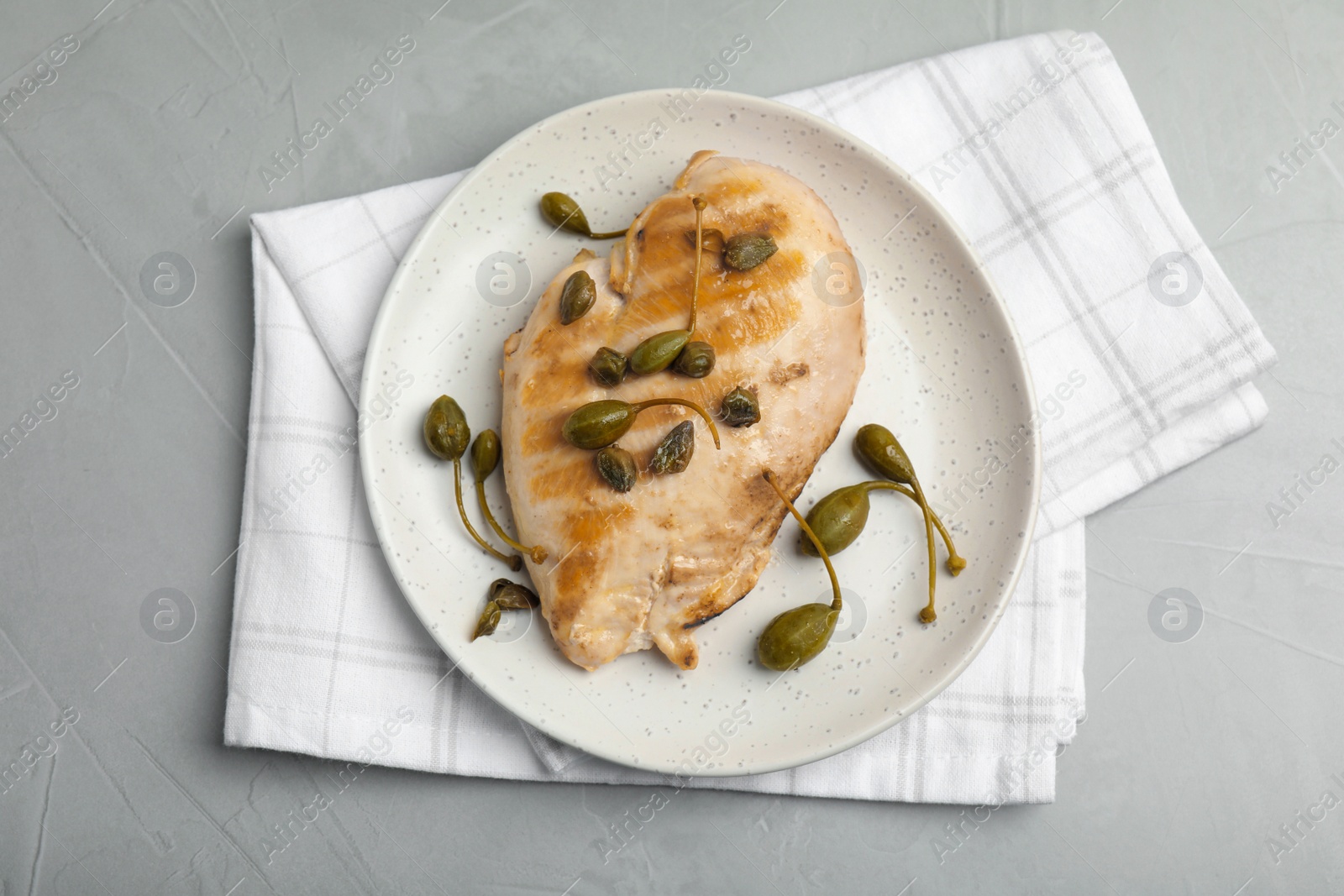 Photo of Delicious cooked chicken fillet with capers served on light grey table, top view