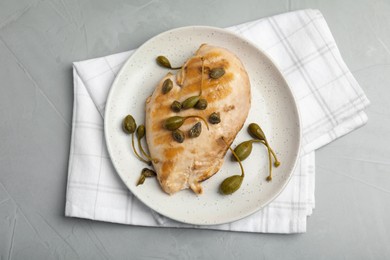 Delicious cooked chicken fillet with capers served on light grey table, top view