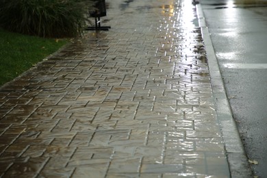 Photo of City street with puddles on pavement after rain