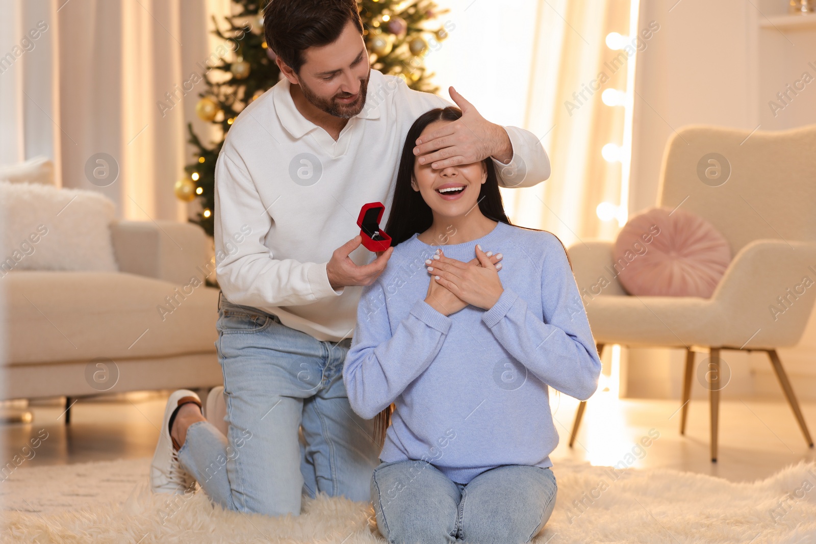 Photo of Making proposal. Man with engagement ring surprising his girlfriend at home on Christmas