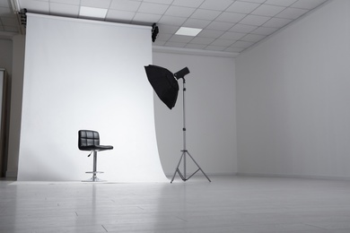 Photo studio interior with modern chair and professional lighting equipment