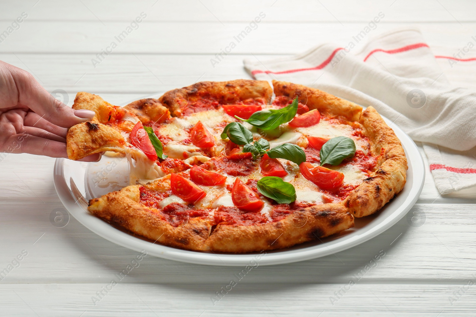 Photo of Woman taking piece of delicious Margherita pizza at white table, closeup