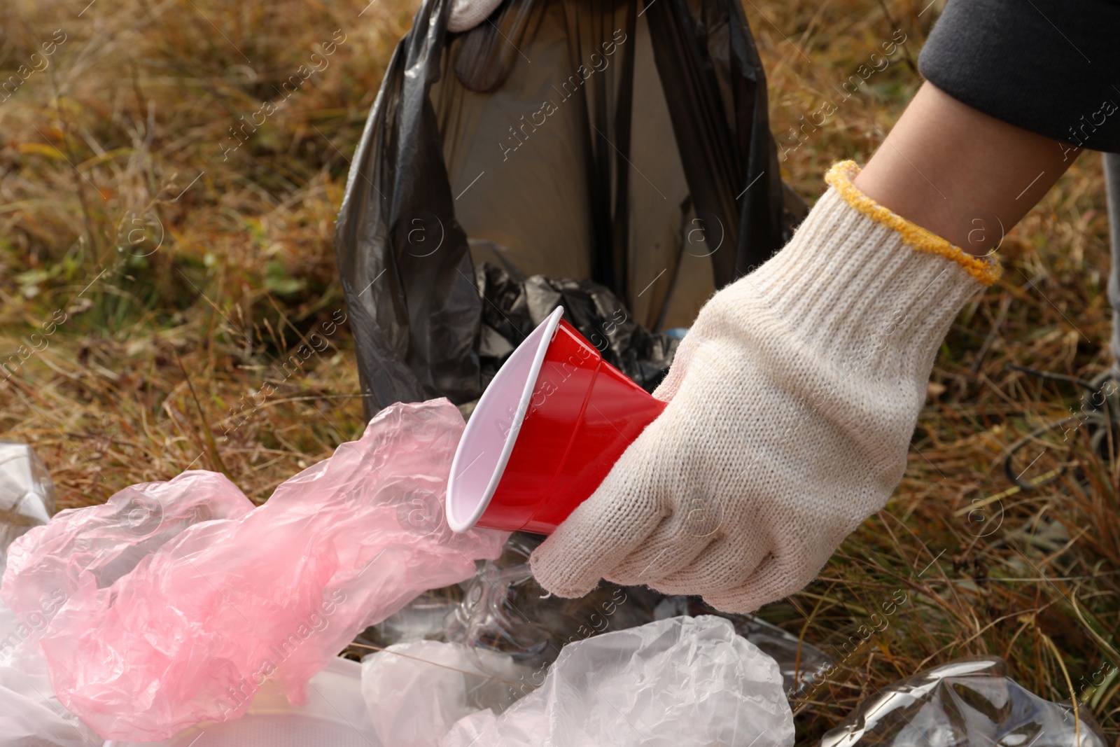 Photo of Woman with trash bag collecting garbage in nature, closeup