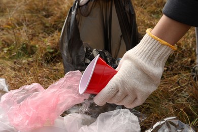 Woman with trash bag collecting garbage in nature, closeup