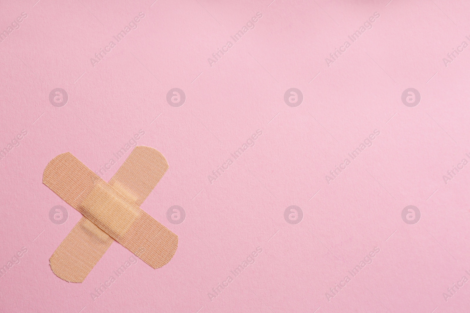 Photo of Sticking plasters on pink background, top view. Space for text