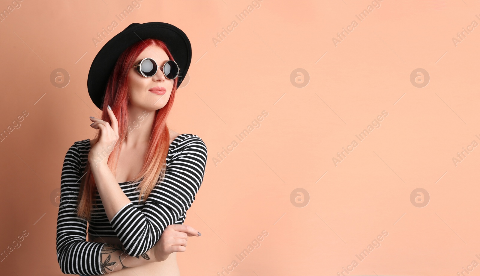 Photo of Young woman with bright dyed hair on pale pink background