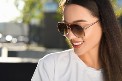 Photo of Beautiful smiling woman in sunglasses outdoors, space for text