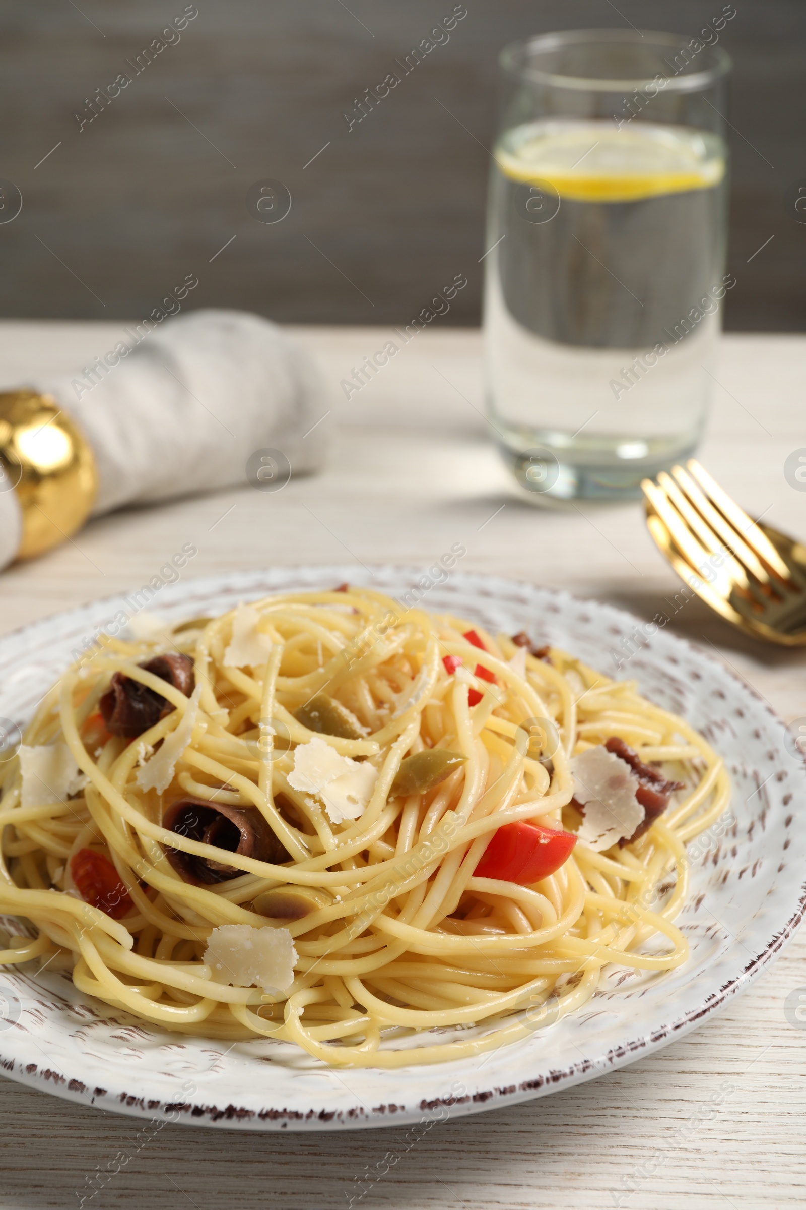 Photo of Delicious pasta with anchovies, tomatoes and parmesan cheese served on white wooden table