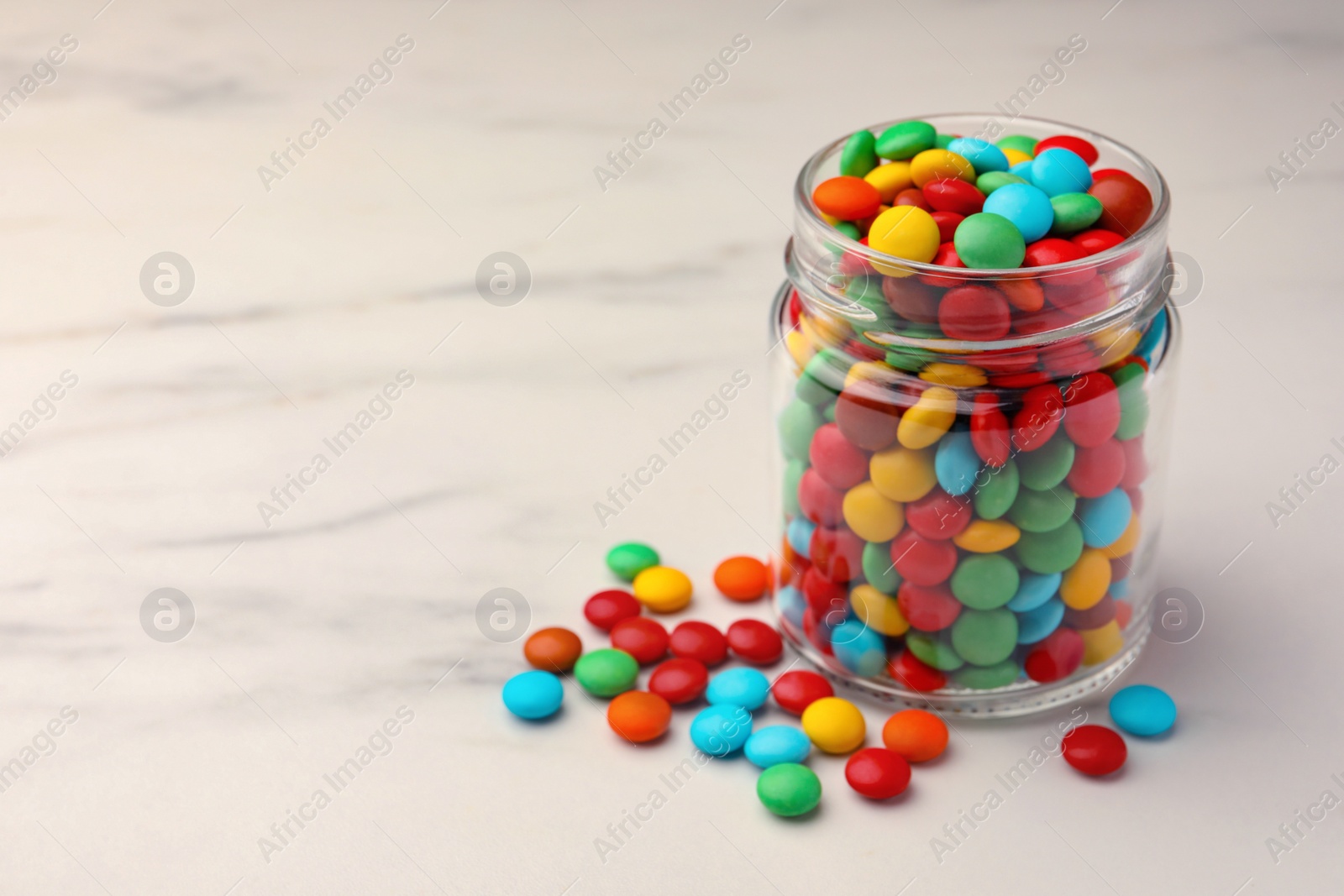 Photo of Tasty colorful candies on white marble table, space for text