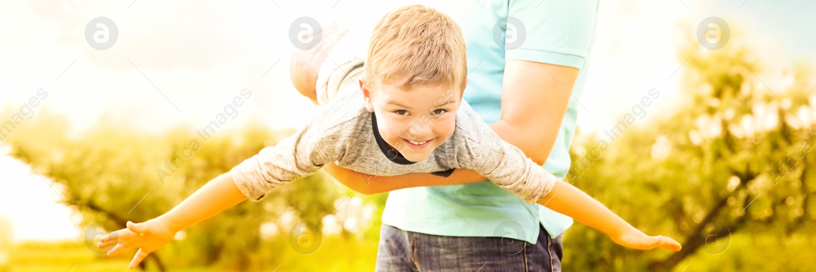 Image of Man playing with his child in park on sunny day. Banner design