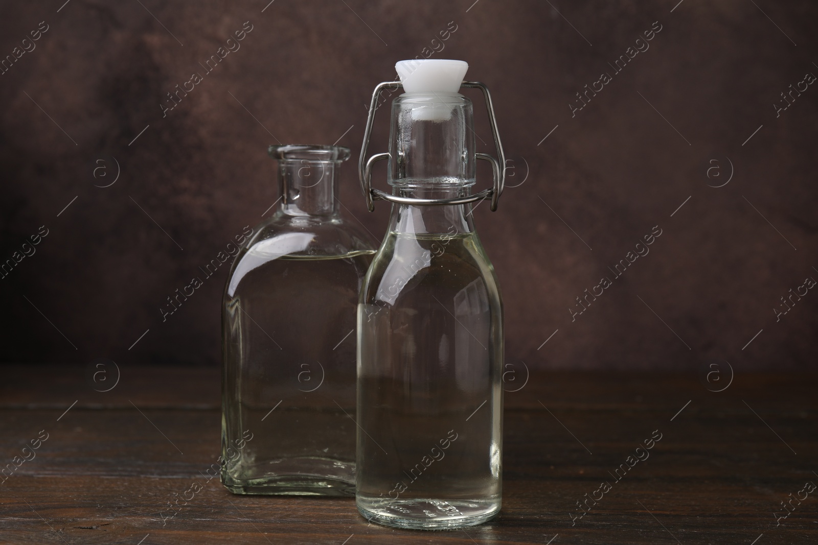 Photo of Vinegar in glass bottles on wooden table