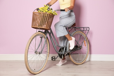 Young woman with bicycle near color wall