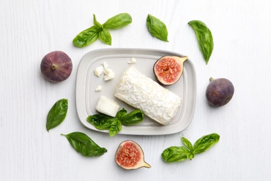 Delicious goat cheese with figs and basil on white wooden table, flat lay