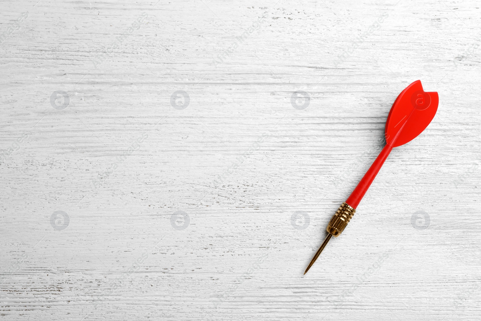 Photo of Red dart arrow on white wooden table, top view with space for text