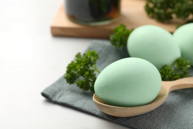 Photo of Turquoise Easter eggs painted with natural dye and curly parsley on table, closeup. Space for text