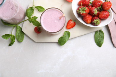 Photo of Tasty milk shake with strawberries on light grey marble table, flat lay. Space for text