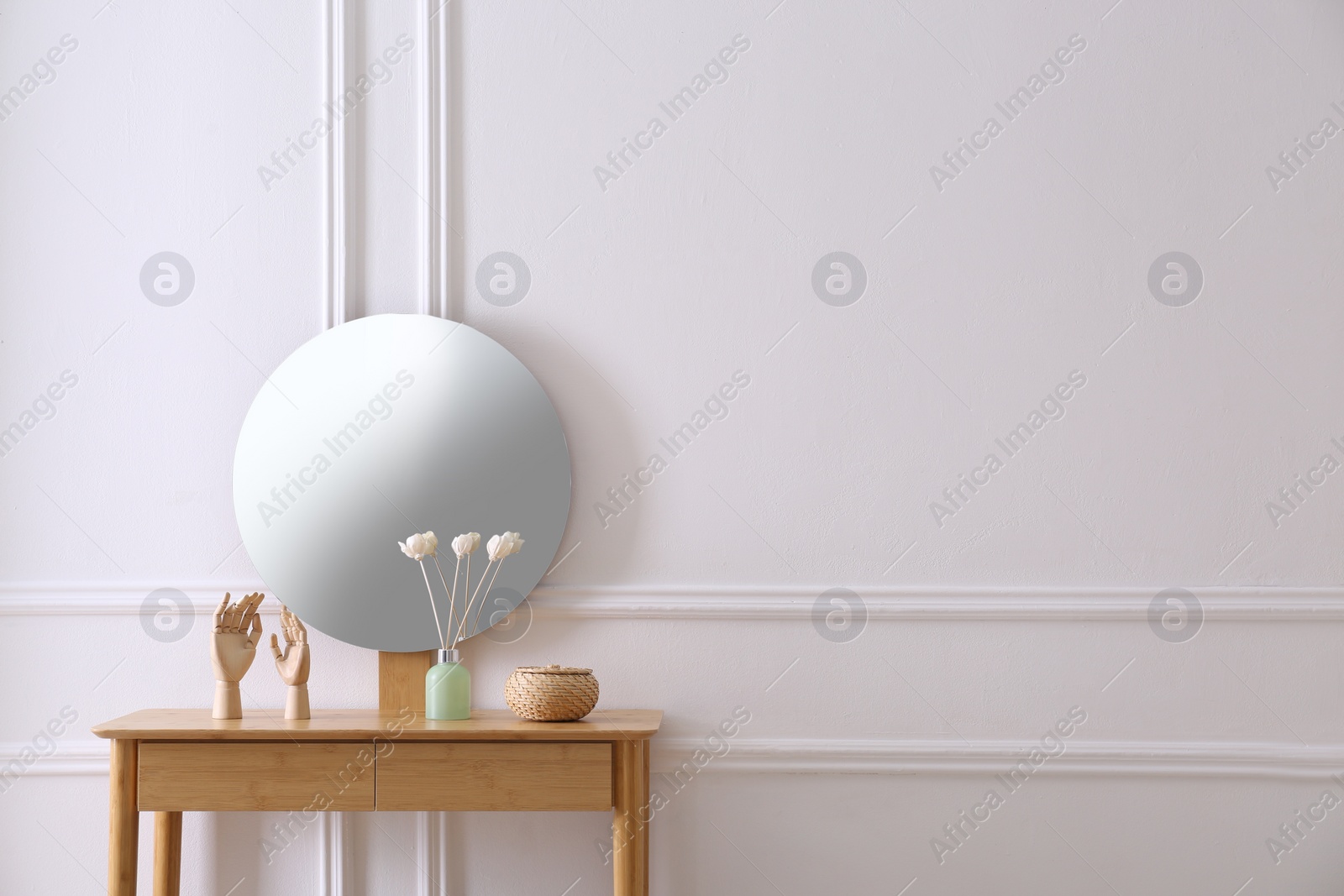 Photo of Air reed freshener and decor on console table near white wall with mirror indoors, space for text. Interior design