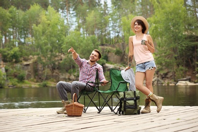 Young couple resting on pier near lake. Camping season