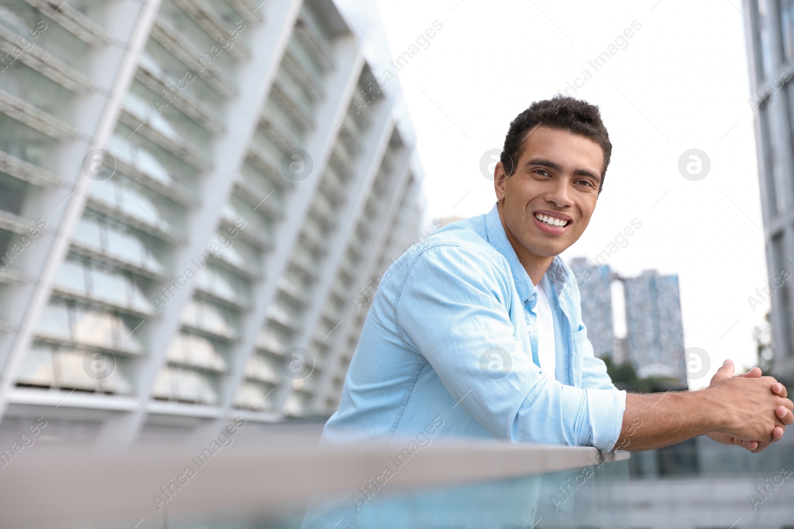 Photo of Portrait of handsome young African-American man on city street. Space for text