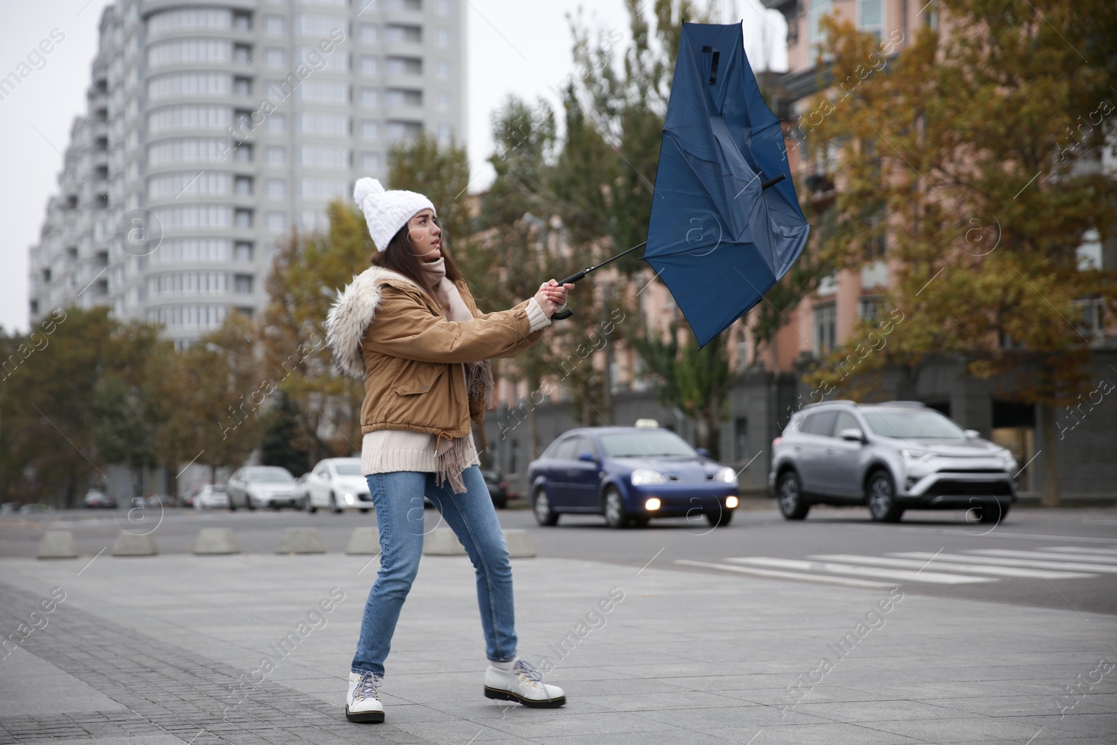 Photo of Woman with blue umbrella caught in gust of wind on street