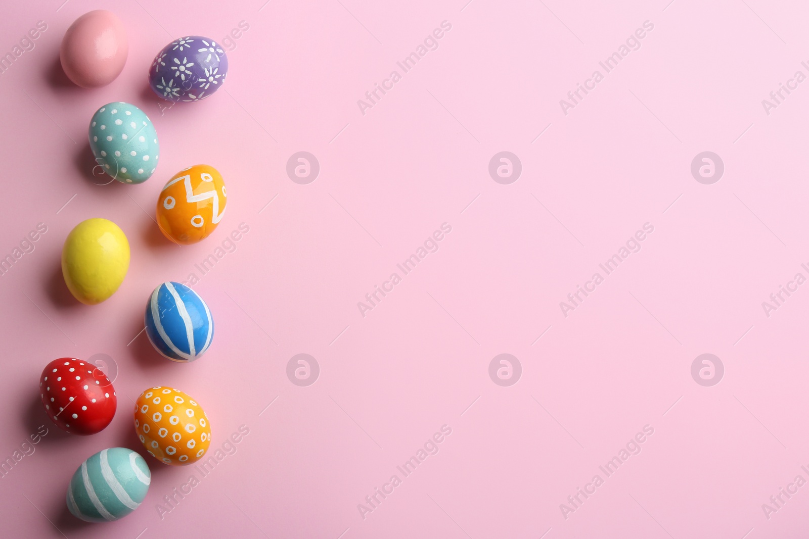 Photo of Flat lay composition of painted Easter eggs on color background, space for text